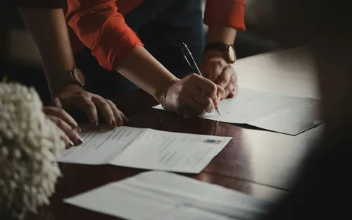 Hands signing legal paperwork — illustration of immediate steps after fraud